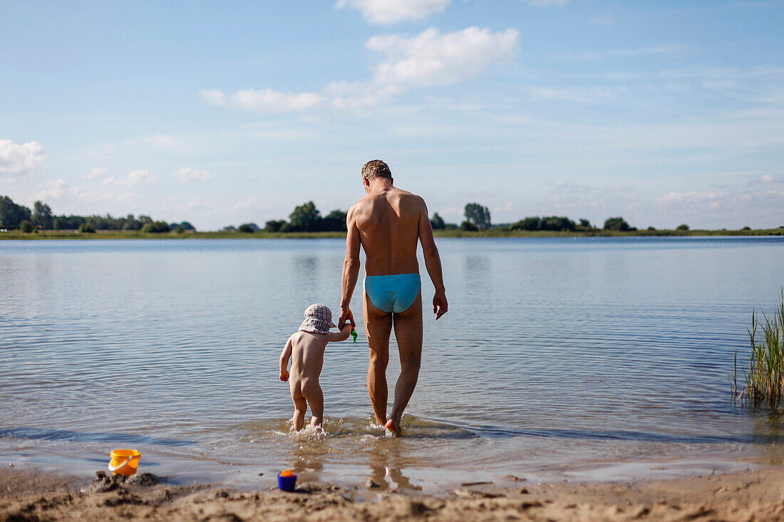 Father and son (2 years) standing in shallow water, Waase, Ummanz, Island of Ruegen, Mecklenburg-Western Pomerania, Germany