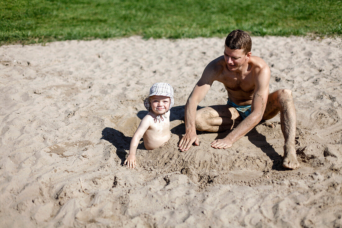 Vater und Sohn (2 Jahre) spielen im Sand, Ummanz, Insel Rügen, Mecklenburg-Vorpommern, Deutschland