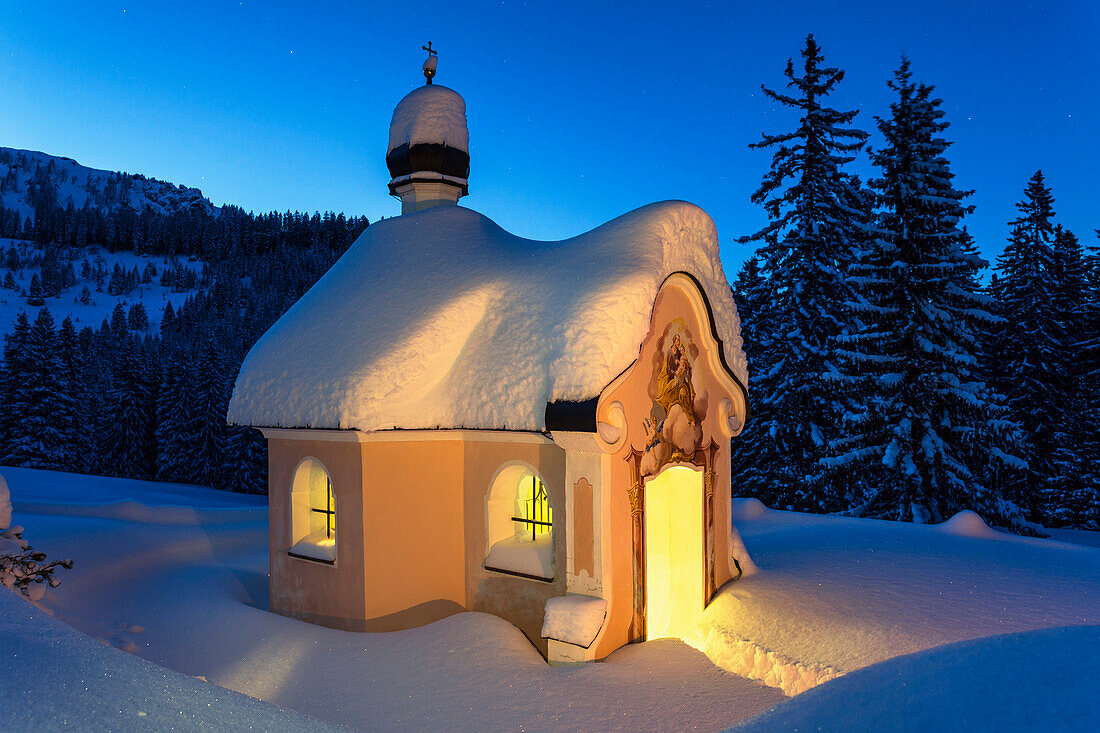 Chapel Maria Koenigin at lake Lautersee in winter with lights,  Mittenwald, Werdenfelser Land, Upper Bavaria, Bavaria, Germany