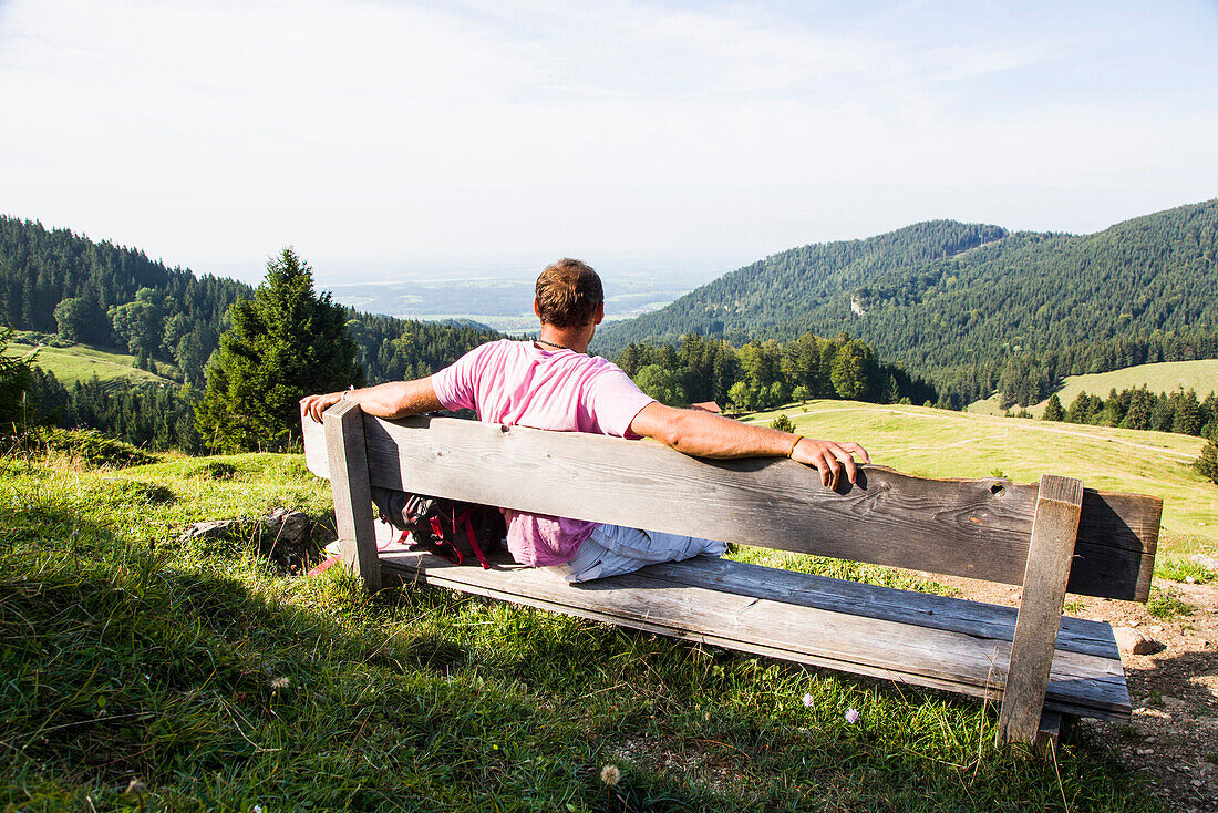Mann sitzt auf einer Bank, Hochries, Riesenhütte, Frasdorf, Chiemgau, Bayern, Deutschland