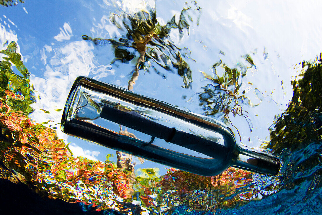 Hawaii, Underwater view of a message in a bottle.