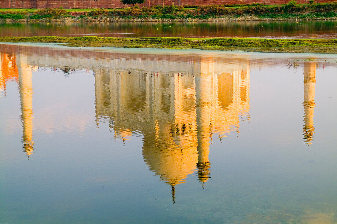 India, Agra, Taj Mahal, temple reflection at sunset on Yamuna River.