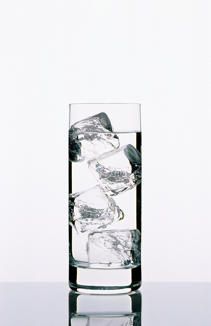 Tall clear glass filled with water and ice cubes.