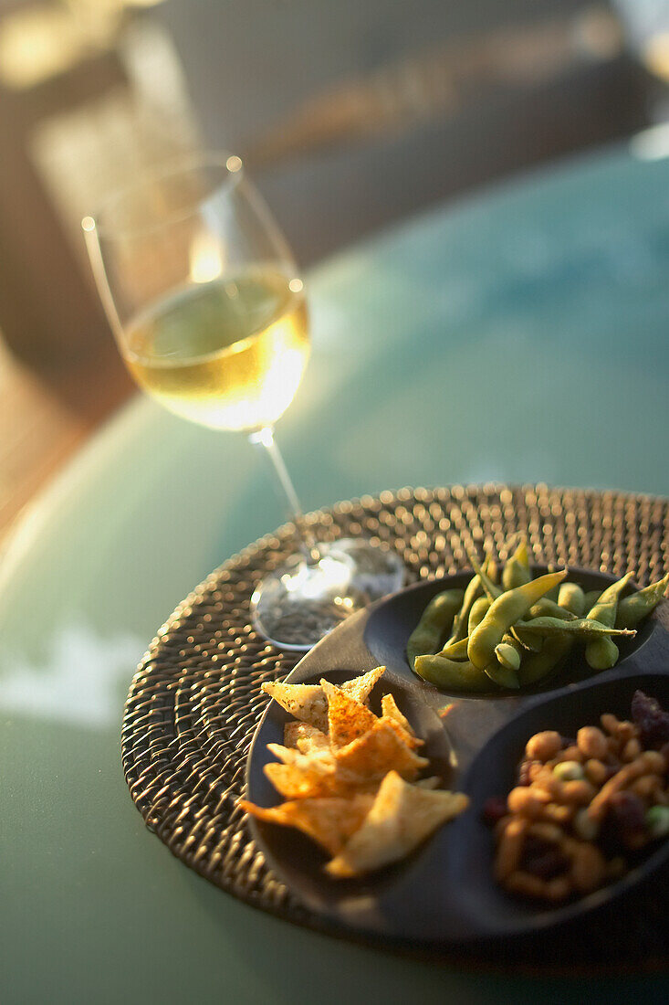 Hawaii, Big Island, Four Seasons Hualalai, white wine in glass and pupus on table.