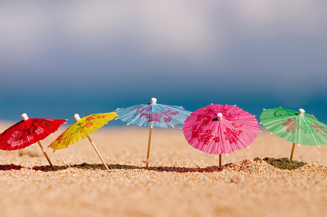 Close-up of cocktail umbrella's in the sand