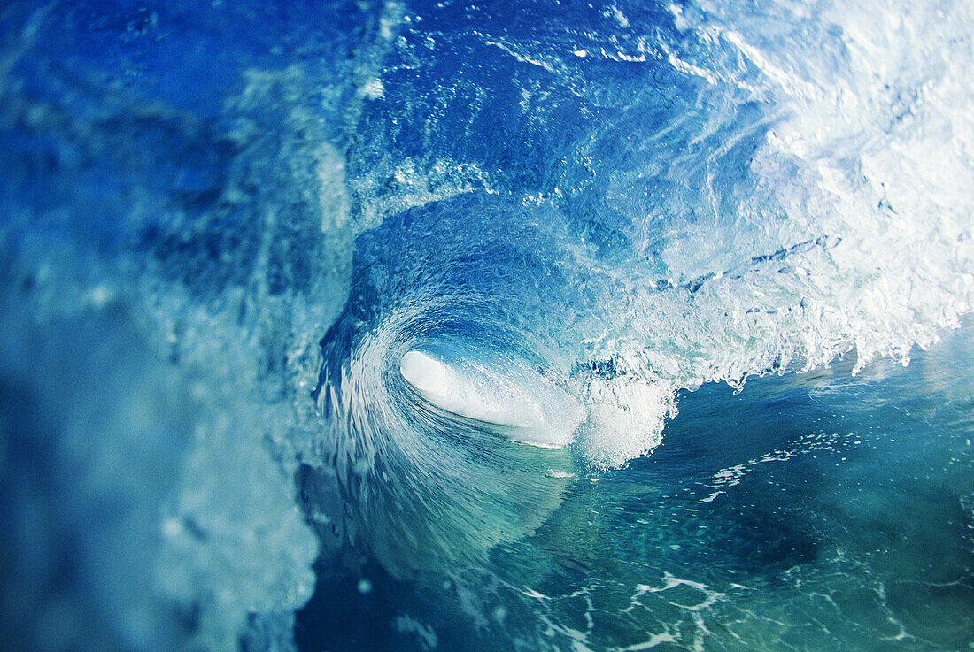 View from inside tube of Inside of wave, circular pattern, sun reflections in the blue water
