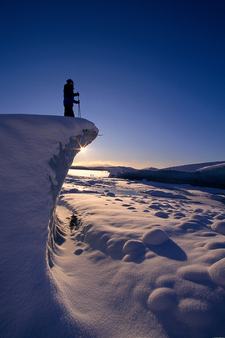 Alaska, Juneau, Mendenhall Glacier, Nordic skier stands on cliff at sunset B1661