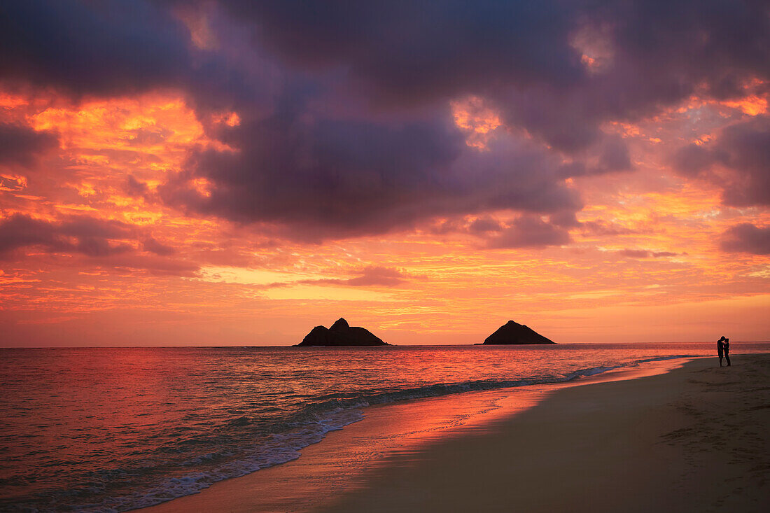 Hawaii, Oahu, Kailua, Lanikai, Vibrant sunset with a couple embracing on beach.