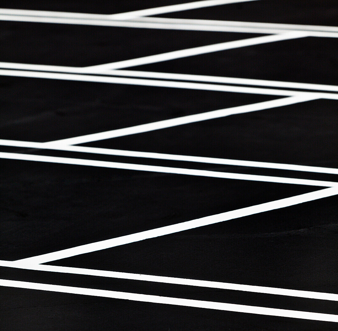 A car park, indoors parking lot, with a freshly resurfaced, black top surface, with newly painted white lines marking the parking bays. Pattern., Los Angeles, California, USA. Parking Lot