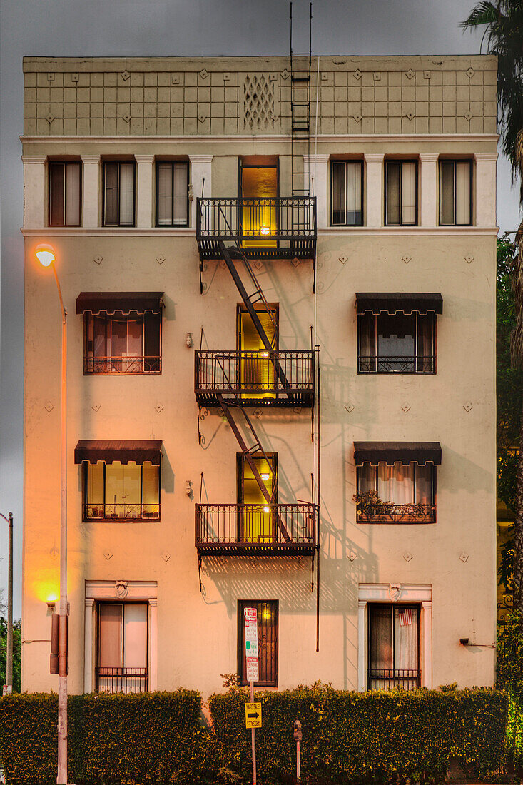 The Villa Rosa apartments building exterior at dusk. A four storey apartment building on Sunset Boulevard, with metal exterior fire escapes. An example of old fashioned, old world, architecture. , Los Angeles, California. Villa Rosa Apartments