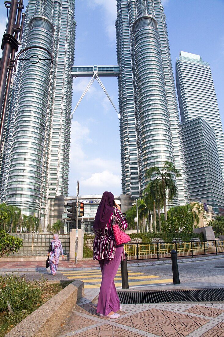 Malaysia, Kuala Lumpur, woman phoning in front of Petronas Towers