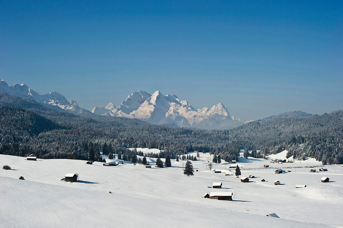 Snow covered huts near Mittenwald, Zugspitze in the background, Bavaria, Germany