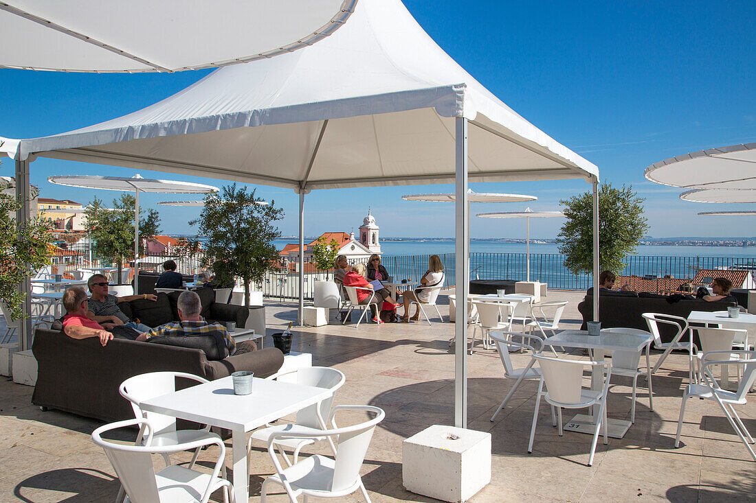 Menschen in Sesseln am Restaurant Esplanada das Portas do Sol am Aussichtspunkt Miradouro de Santa Luzia in der Alfama, Lissabon, Portugal