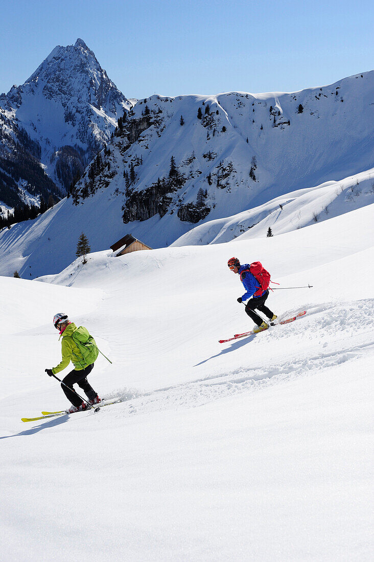 Two backcountry skiers downhill skiing from Brechhorn, Grosser Rettenstein in background, Kitzbuehel Alps, Tyrol, Austria
