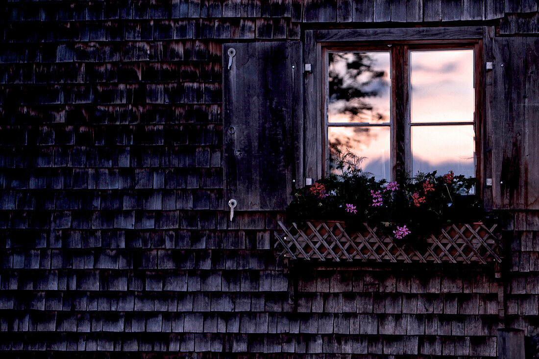 Fenster einer Hütte in den Bergen bei Sonnenuntergang, Oberberg, Bayern, Deutschland