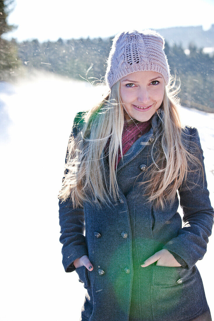 Junge Frau steht im Schneefall, Steiermark, Österreich