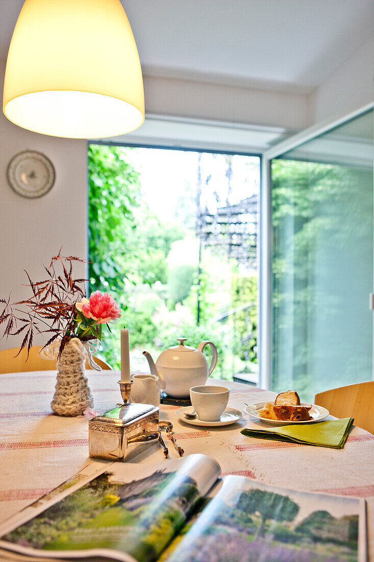 Tee und Kuchen mit Magazin, gedeckter Tisch im Wohnzimmer mit dem blick in Garten, Wien, Österreich