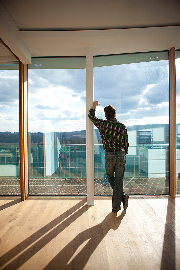 Ein Mann schaut in den Himmel durch das Fenster, Passivhaus, Steiermark, Österreich