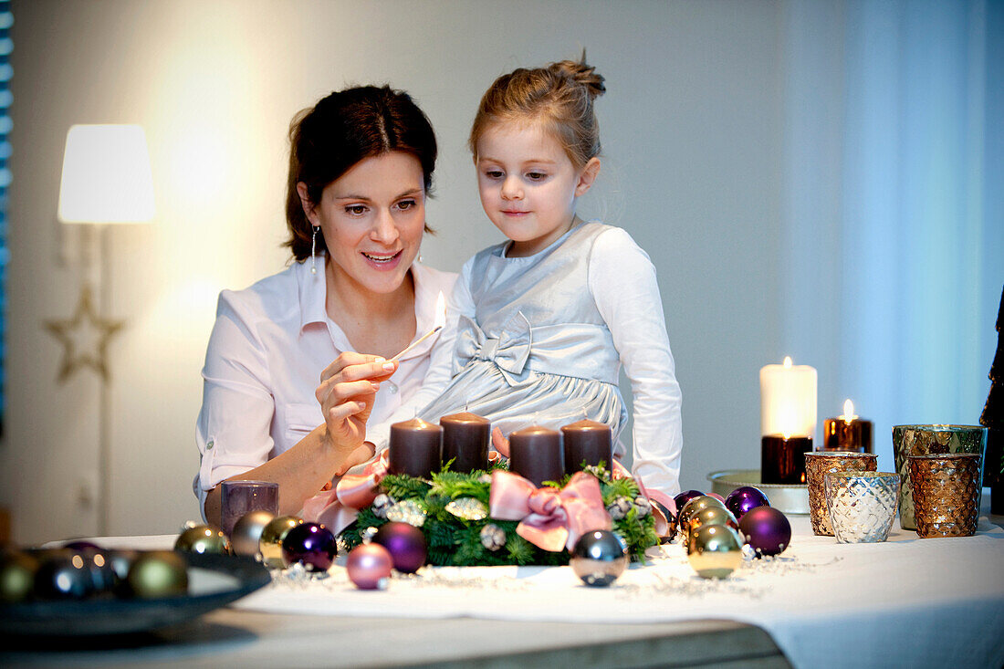 Mother and daughter (4 years) lighting candle on an Advent wreath
