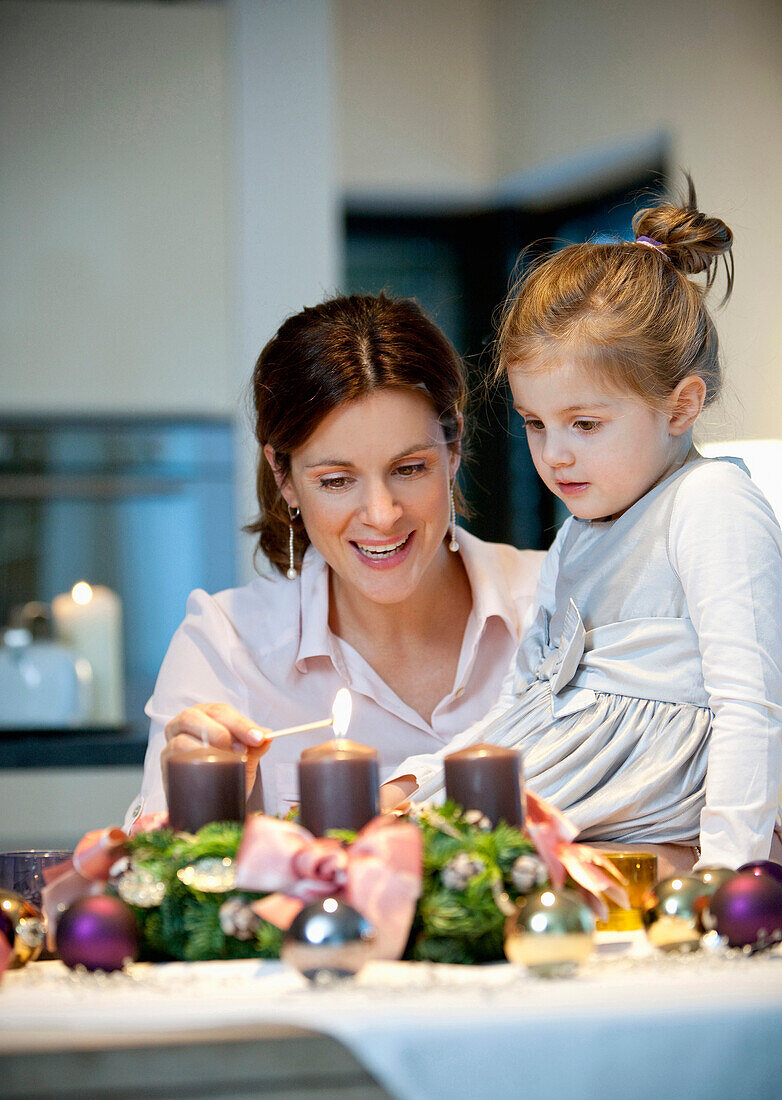 Mother and daughter  lighting candle on an Advent wreath, Styria, Austria