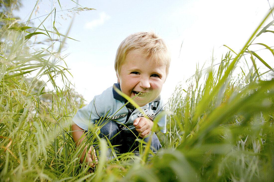 Junge (3 Jahre) hockt im Gras, Wien, Österreich