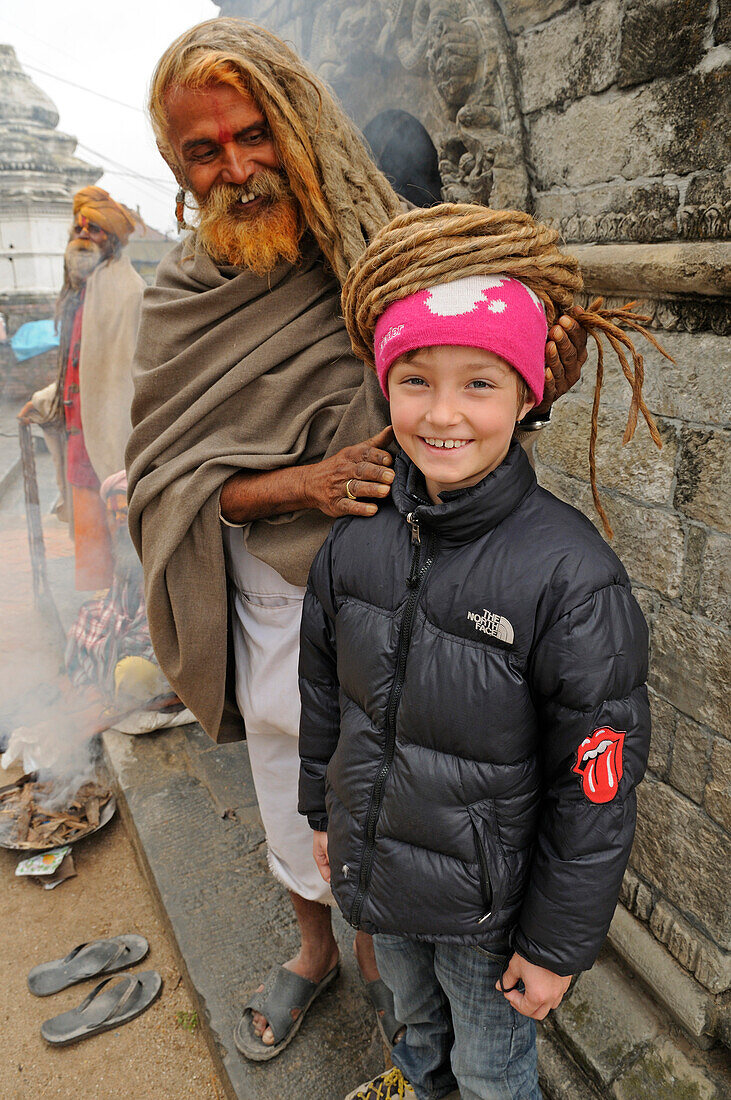 Sadhu mit Rastazöpfen, Asket mit Kind von Touristen, Pashupatinath, Kathmandu Valley, Nepal