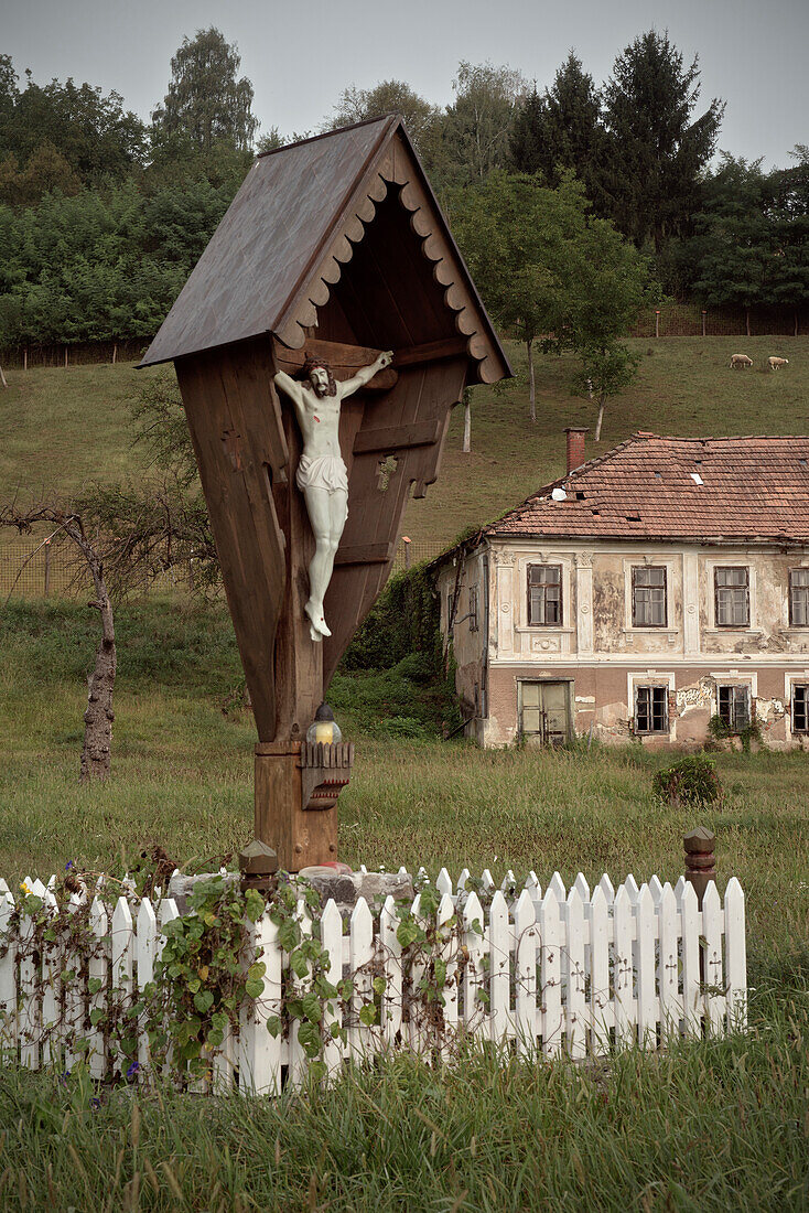 Jesus at cross in front of deserted house, rural Krsko, Dolenjska, Bela Krajina, Slovenia
