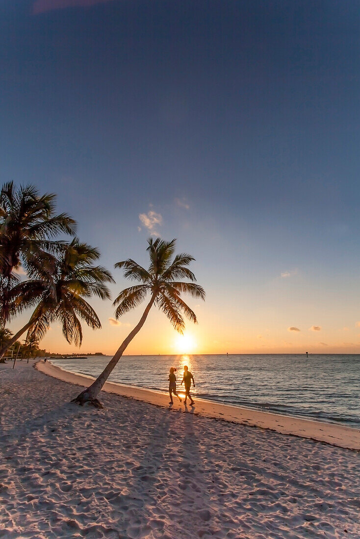 Morning impression with couple jogging along the beach at sunrise, Key West Smathers Beach, Key West, Florida Keys, Florida, USA