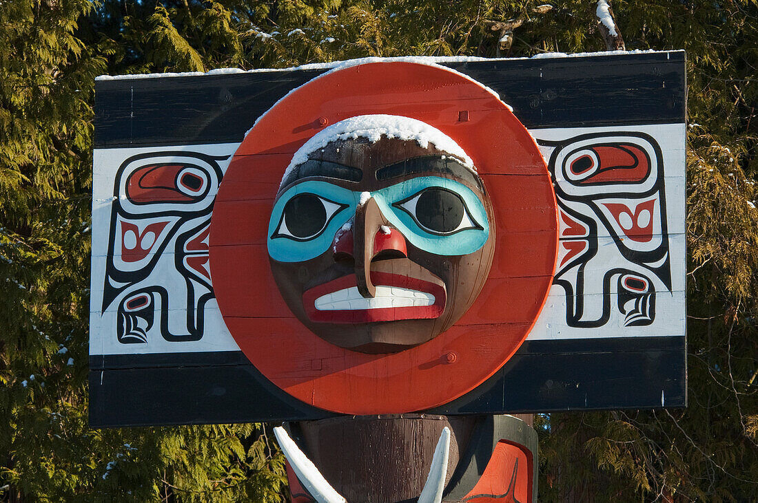 Moon on Chief Skedans Mortuary Pole carved in Haida style by Bill Reid with Werner True covered in snow in Stanley Park, Vancouver, British Columbia, Canada