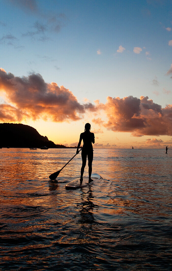 Hawaii, Kauai, Woman stand up paddling in ocean, Beautiful sunset.