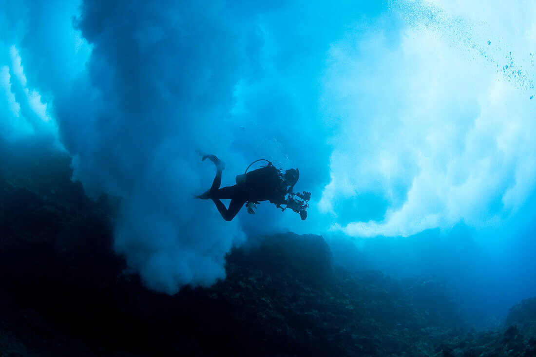Hawaii, Lanai, Scuba diver under billowing surf breaking over reef.