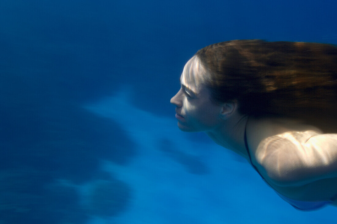 Hawaii, Big Island, Honaunau Bay, Young woman swims underwater.