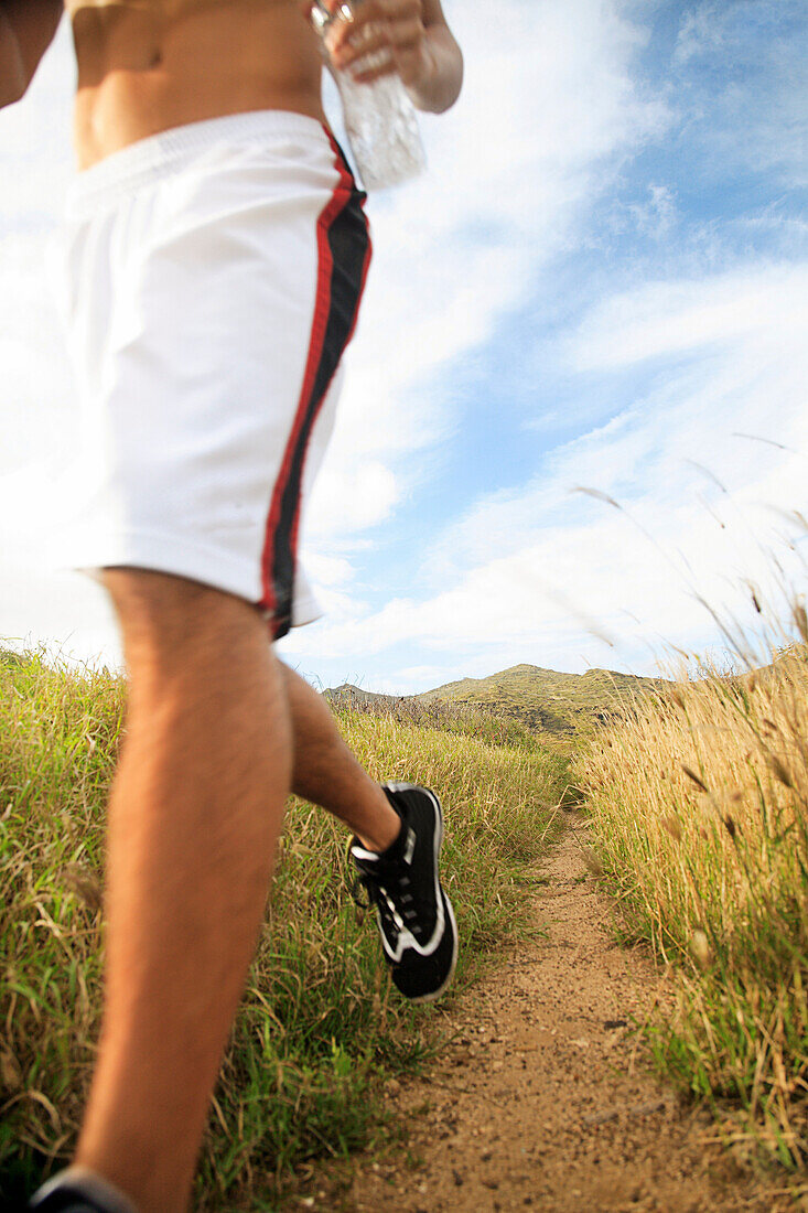 Hawaii, Oahu, Atheltic Male jogging on an outdoor field walkway path