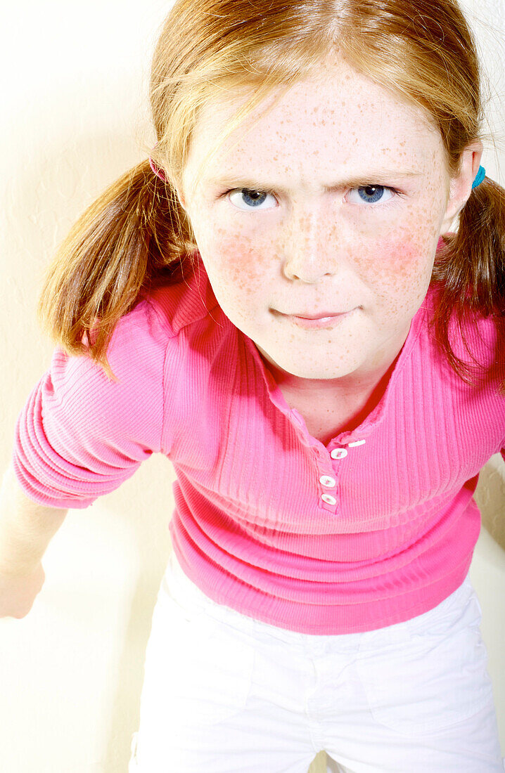 Young girl with freckles and red hair in pigtails poses in the studio.
