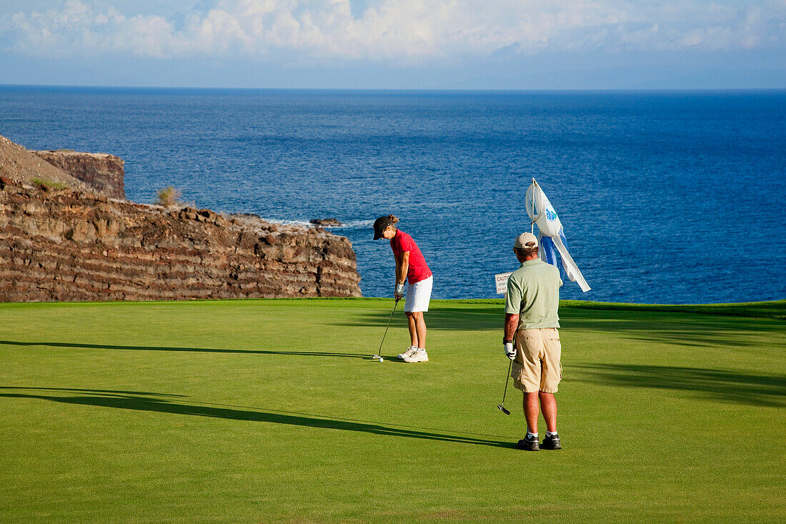 Hawaii, Lanai, Couple putting on the green at The Challenge at Manele golf course.