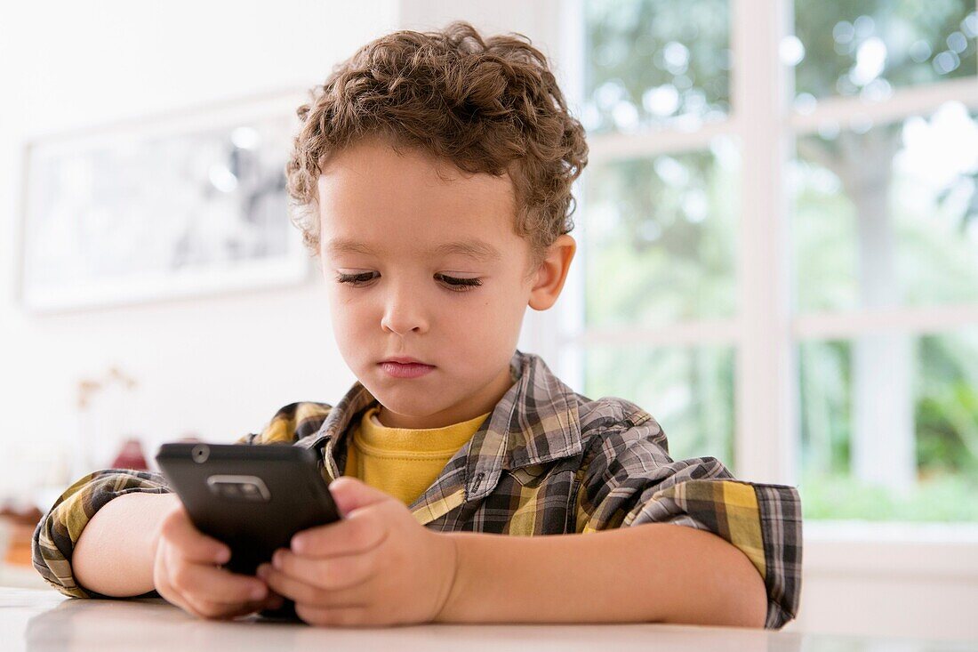 Four year old boy playing games on a cell phone
