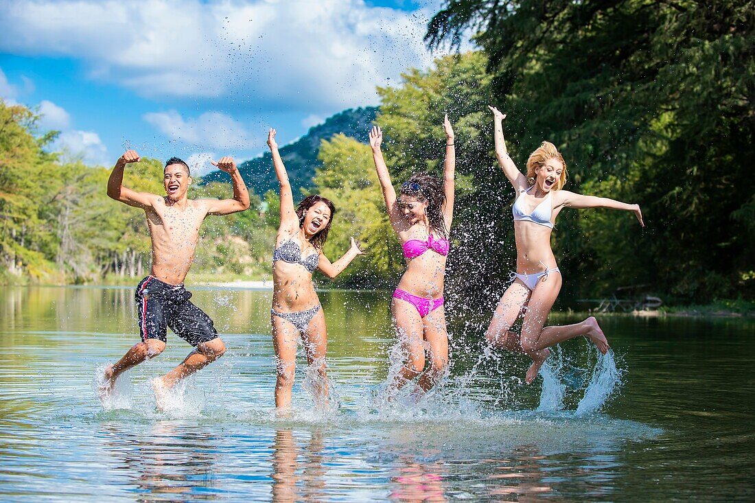 Group of teenagers having summer fun while jumping out of the water