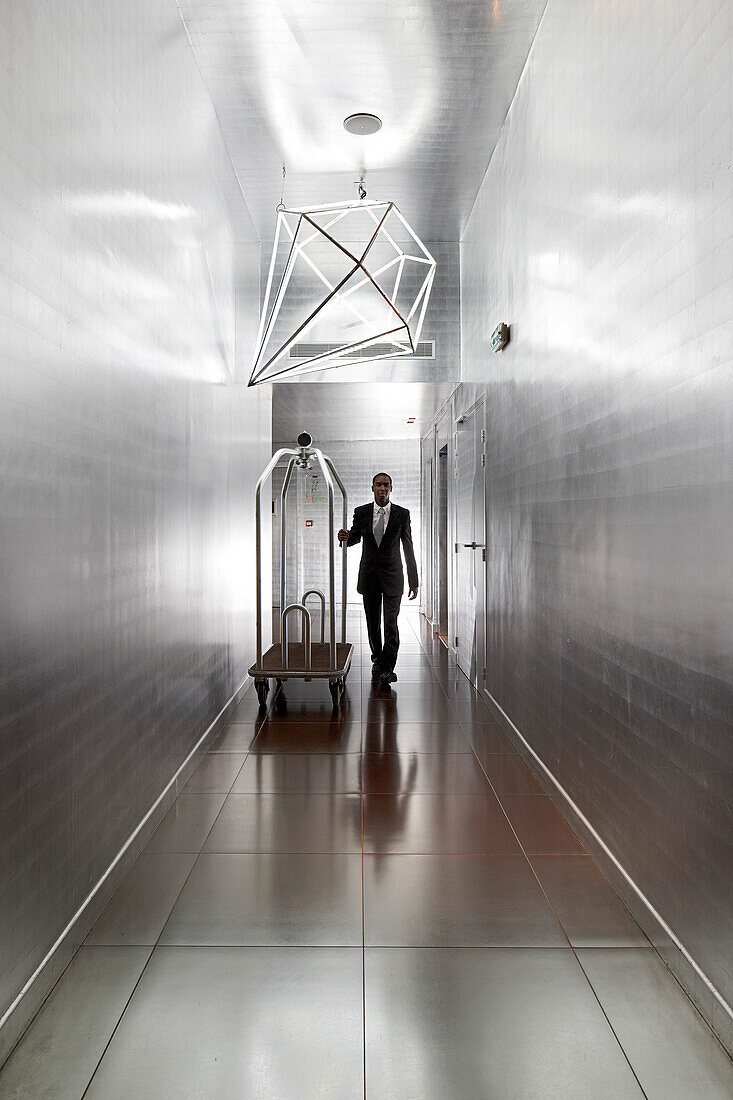 Hotel clerk in the silver hallway with walls covered in aluminium, Hotel La Maison Champs-Elysees, designed by Martin Margiela, Paris, France