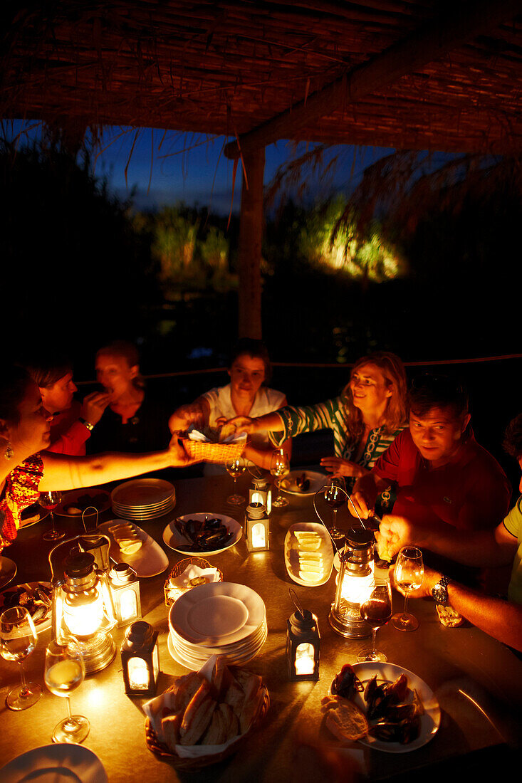 Gäste essen zu Abend auf der Holzterrasse mit Öllampen, Hotel Areias do Seixo, Povoa de Penafirme, A-dos-Cunhados, Costa de Prata, Portugal