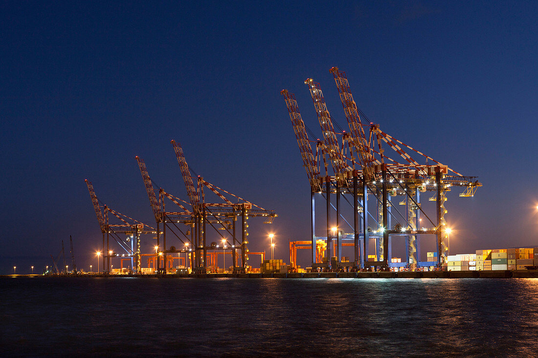 Cranes in shipyard lit up at night