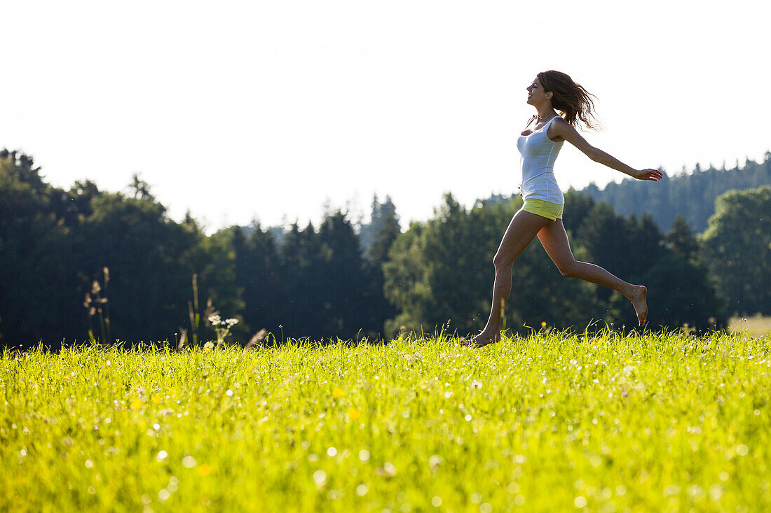 Young woman running over a meadow, Upper Bavaria, Germany