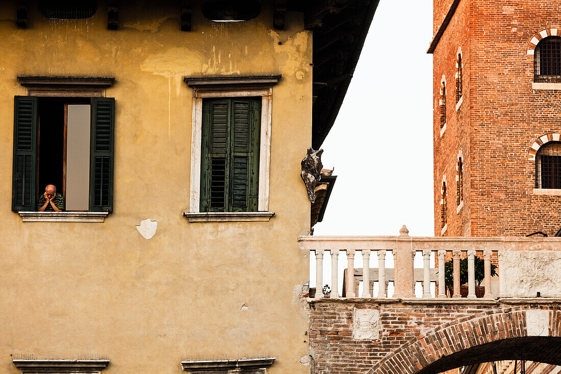 Alter Mann schaut aus einem Fenster, Piazza delle Erbe, Verona, Venetien, Italien
