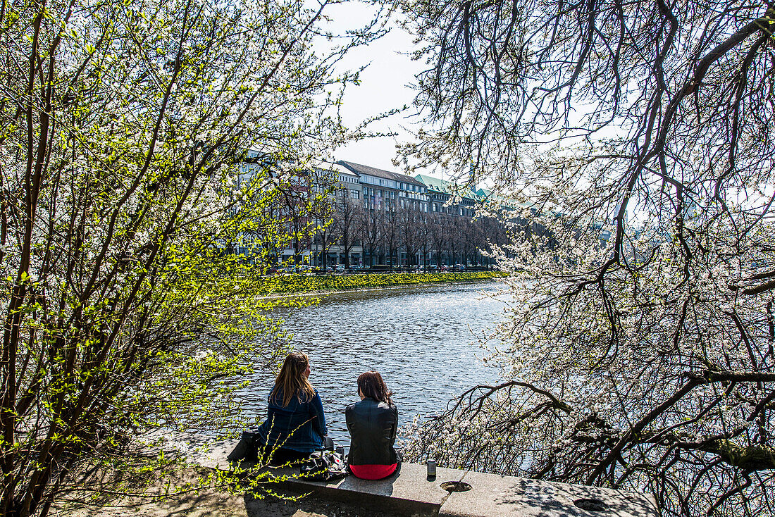 Two young woman sitting on a wall, Binnenalster of Hamburg in springtime, Hamburg, Northern Germany, Germany