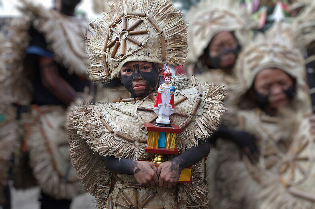 Young girl holding a Santo Nino figur, Ati Atihan Festival, Kalibo, Aklan, Western Visayas Region, Panay Island, Philippines