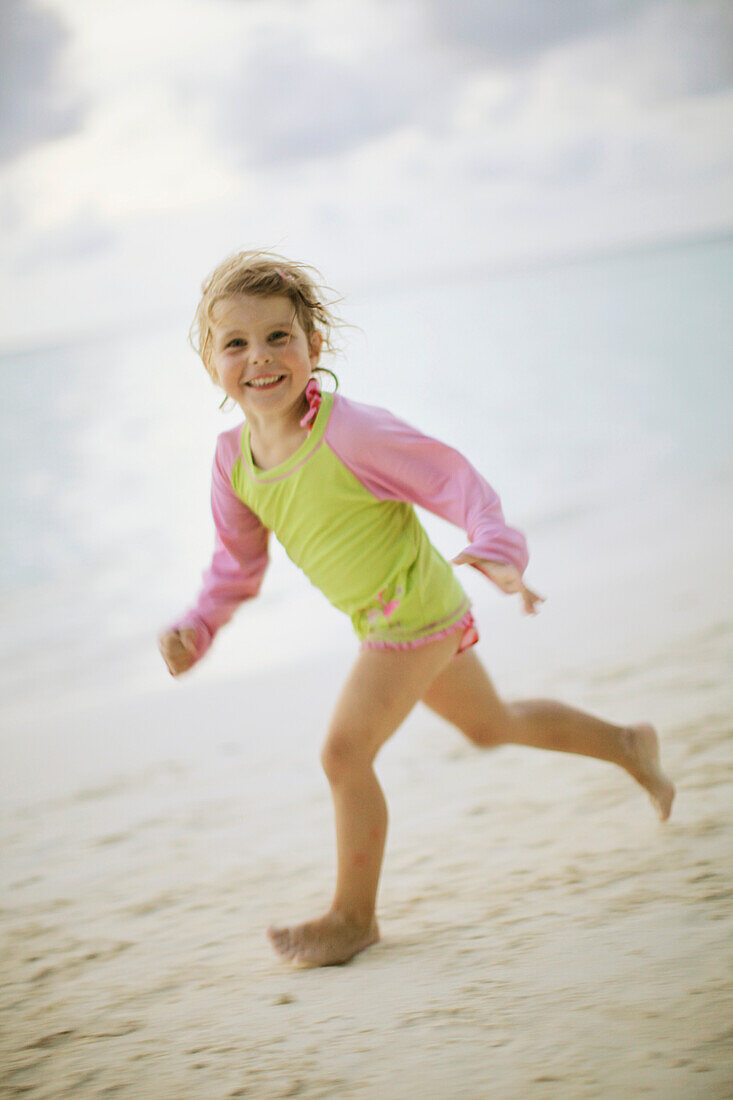 Girl running along beach, Biyadhoo Island, South Male Atoll, Maldive Islands