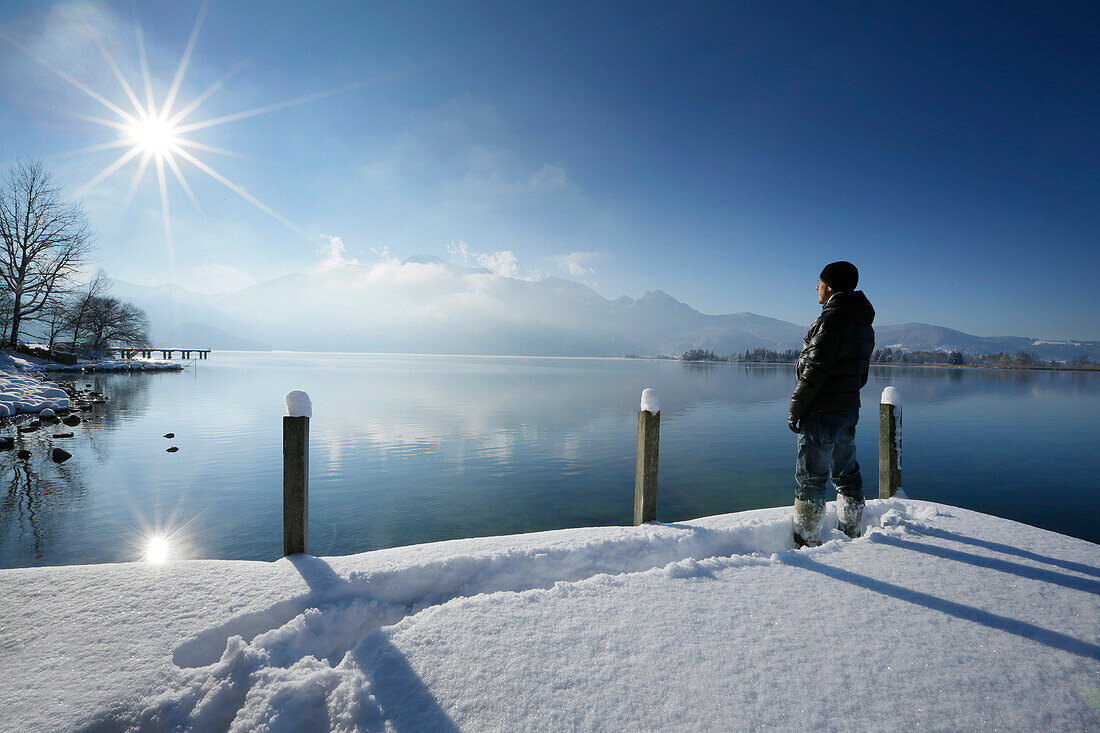 Man standing on snow-covered jetty at lake Kochel, Upper Bavaria, Germany