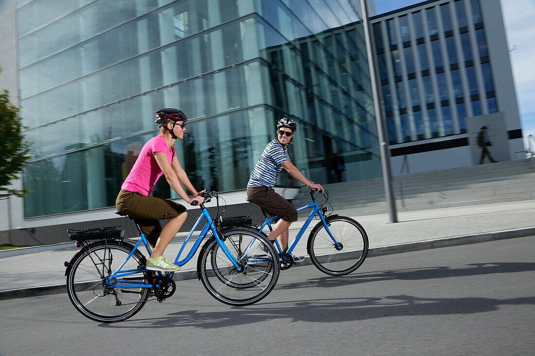 Couple riding e-bikes, Munich, Bavaria, Germany