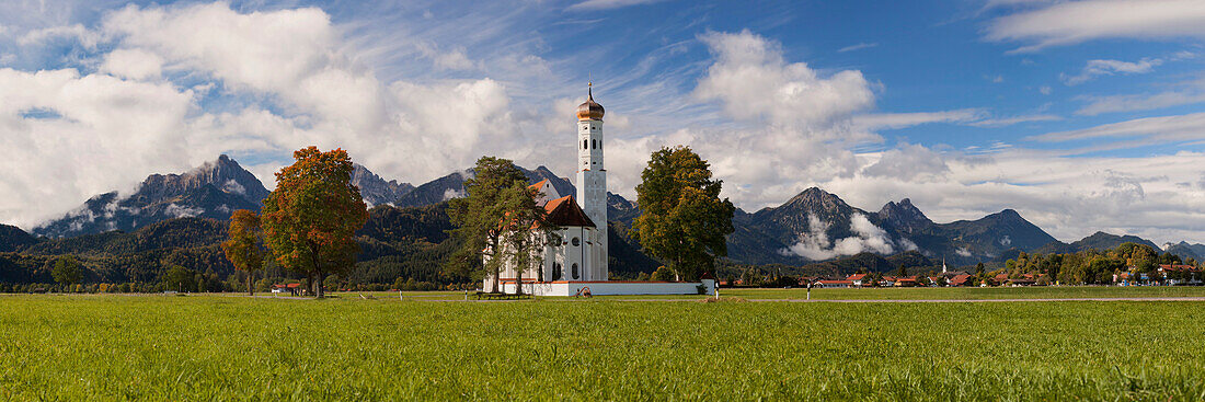 Idyllischer Blick auf die barocke Kirche St. Coloman nahe Schwangau mit dem Tannheimer Gebirge im Hintergrund, Bayern, Deutschland