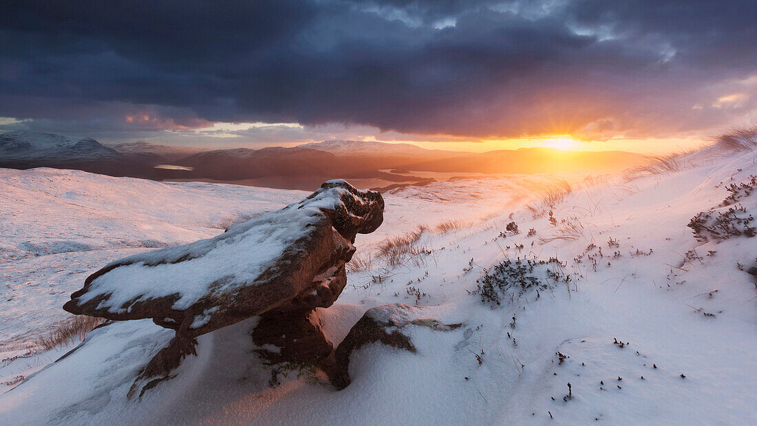 Fantastic sunset over the snow-covered North West Highlands with wind cut Torridon sandstone in the foreground, Ullapool, Scotland, United Kingdom
