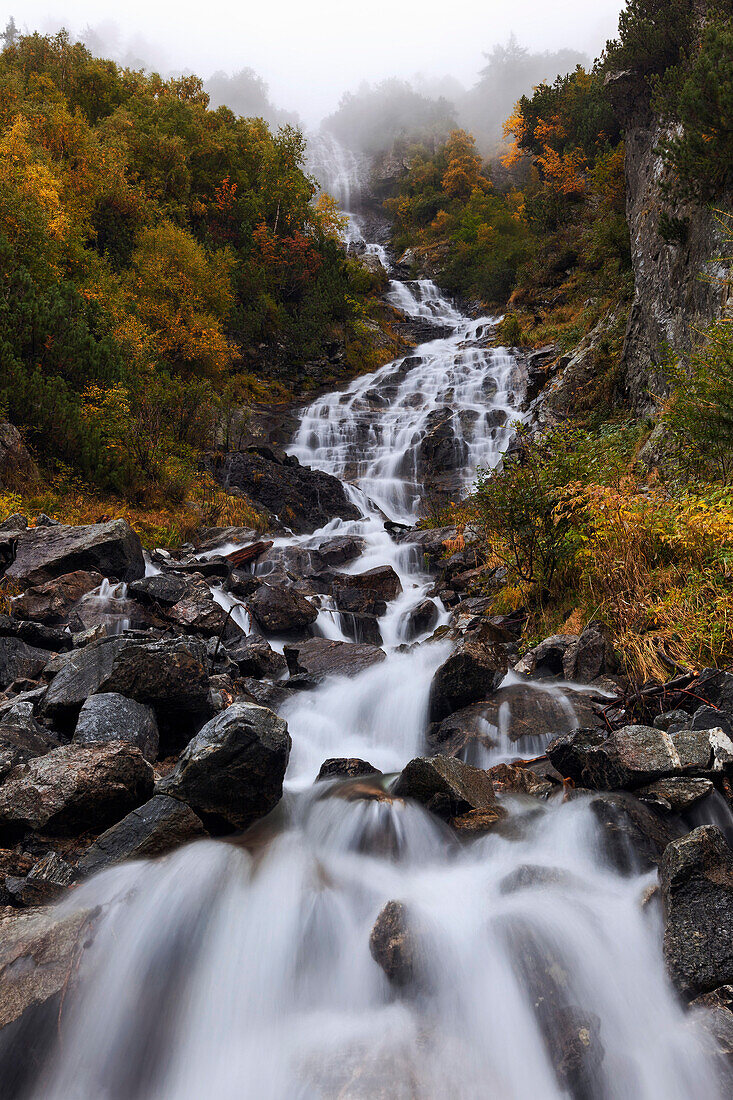 Imposanter Wasserfall im Val Bondasca an einem nebeligen Herbsttag, Bergell, Schweiz